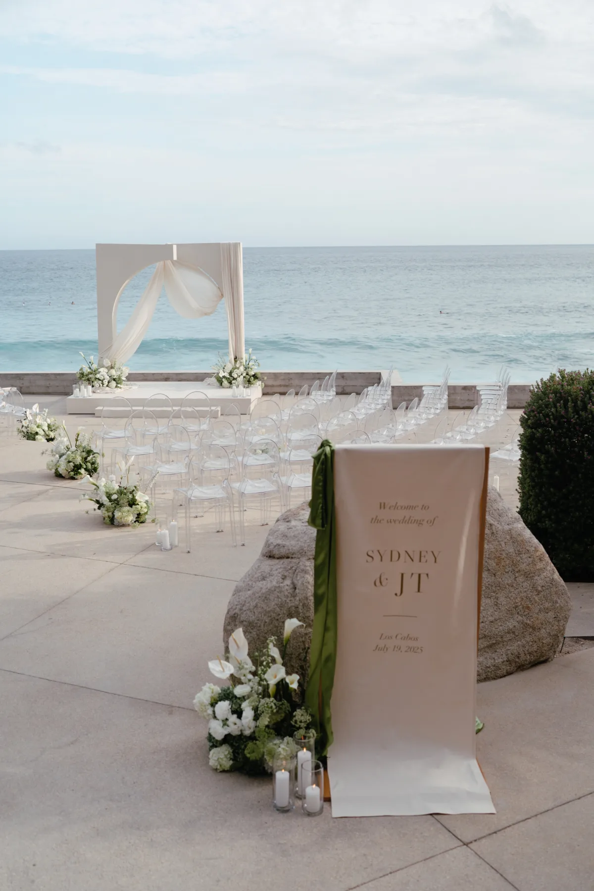 luxury cabo beach wedding ceremony setup aria vera floral cape thompson hotel - Luxury Cabo Wedding at The Cape, a Thompson Hotel Elegant beachfront wedding ceremony setup with white florals by Aria Vera Floral at The Cape, a Thompson Hotel in Cabo San Lucas featuring clear ghost chairs and ocean views