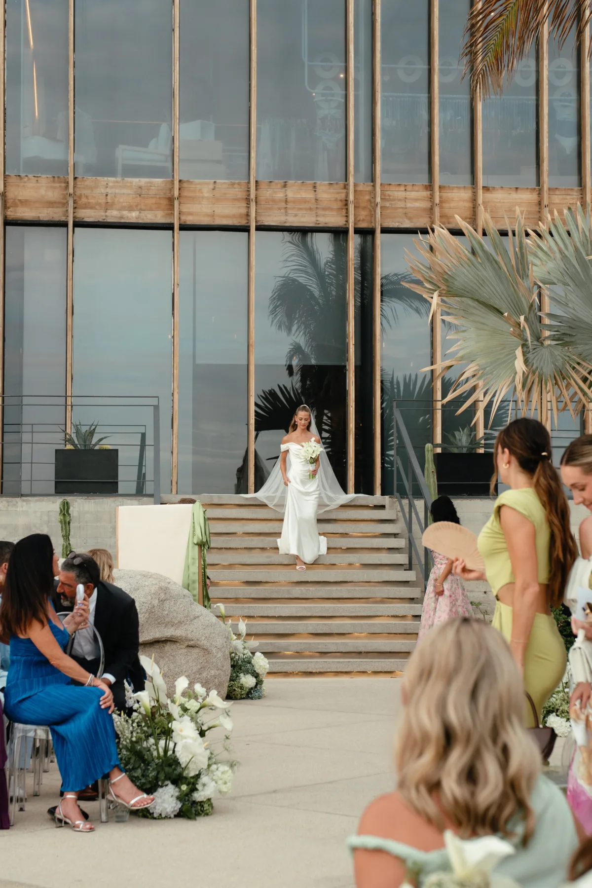luxury cabo destination wedding ceremony engaging events ali the cape thompson hotel - Luxury Cabo Wedding at The Cape, a Thompson Hotel Bride walking down stairs at luxury Cabo destination wedding ceremony at The Cape Thompson Hotel with tropical palm trees and modern architecture, planned by Chicago wedding planner Engaging Events by Ali
