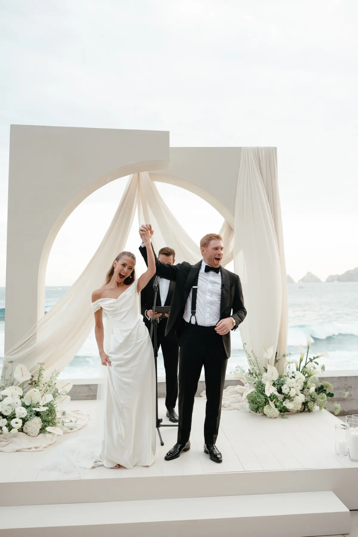 luxury cabo destination wedding ceremony engaging events by ali chicago wedding planner - Luxury Cabo Wedding at The Cape, a Thompson Hotel Newlyweds celebrate after luxury destination wedding ceremony at The Cape Thompson Hotel in Cabo San Lucas with white floral arrangements by Aria Vera Floral and wedding planning by Chicago-based Engaging Events by Ali