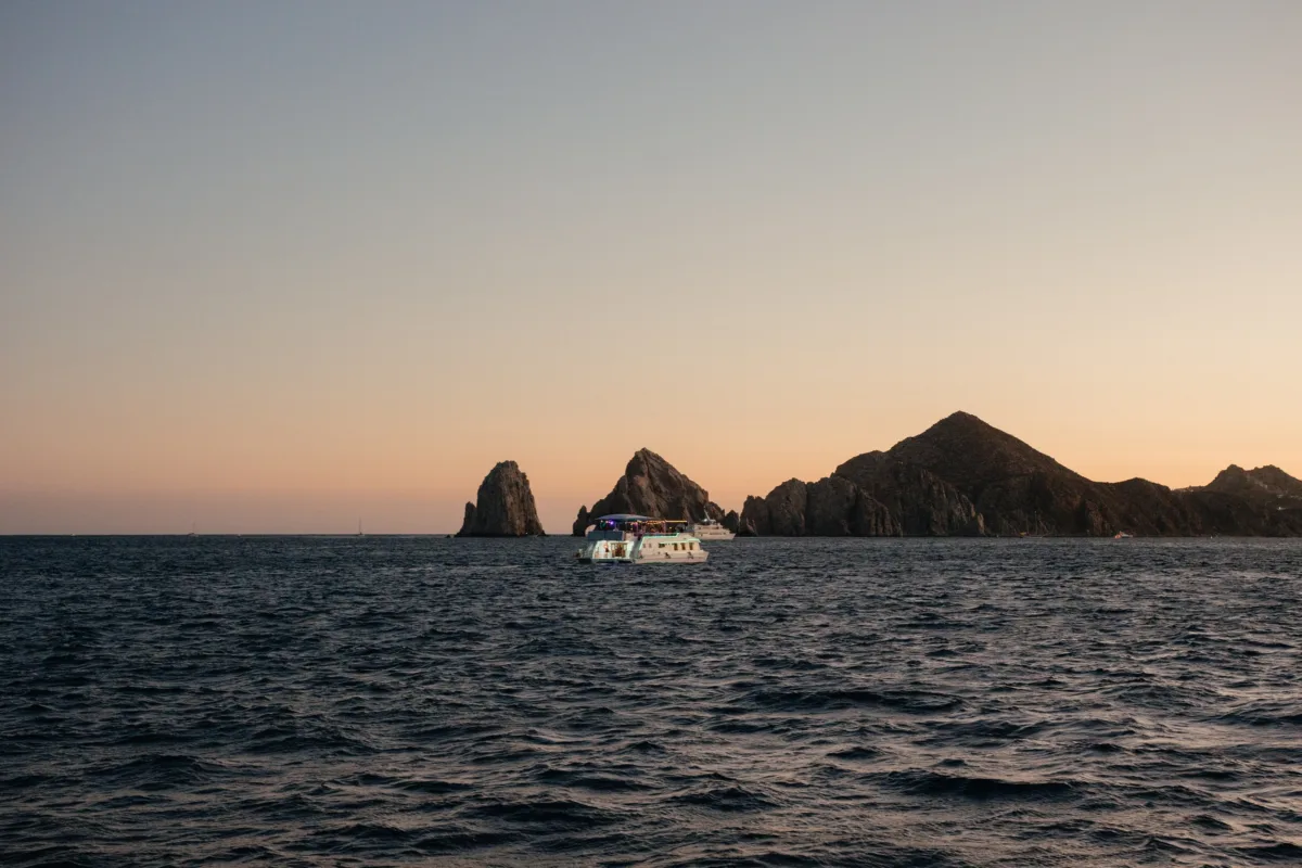luxury cabo destination wedding thompson hotel sunset cruise - Luxury Cabo Wedding at The Cape, a Thompson Hotel Sunset boat cruise during luxury destination wedding celebration at The Cape Thompson Hotel in Cabo San Lucas with dramatic rock formations