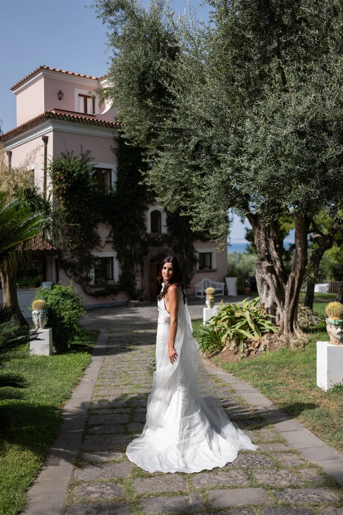 amalfi coast destination wedding planning engaging events ali capo santa fortunata sorrento - An Effortless Amalfi Coast Celebration Bride in flowing white gown on stone pathway at Capo Santa Fortunata villa in Sorrento Italy, planned by Engaging Events by Ali for destination Amalfi Coast wedding