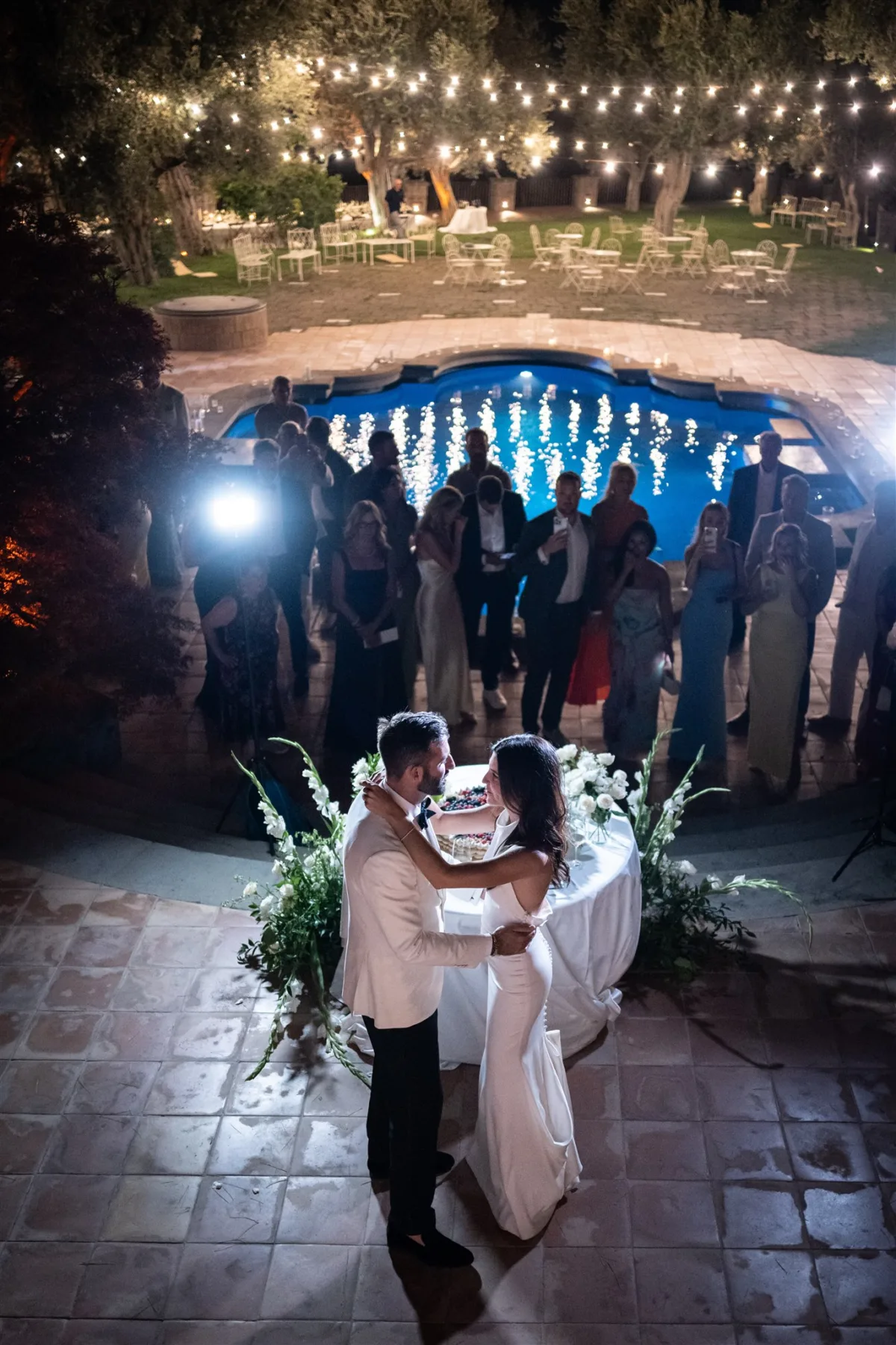 amalfi coast destination wedding planning engaging events by ali capo santa fortunata - An Effortless Amalfi Coast Celebration Couple cutting wedding cake at nighttime poolside celebration in Sorrento Italy planned by Engaging Events by Ali at Capo Santa Fortunata venue