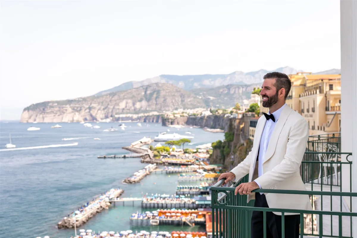 amalfi coast destination wedding planning engaging events by ali sorrento - An Effortless Amalfi Coast Celebration Groom in white tuxedo overlooking Mediterranean coastline during destination wedding in Sorrento Italy planned by Engaging Events by Ali