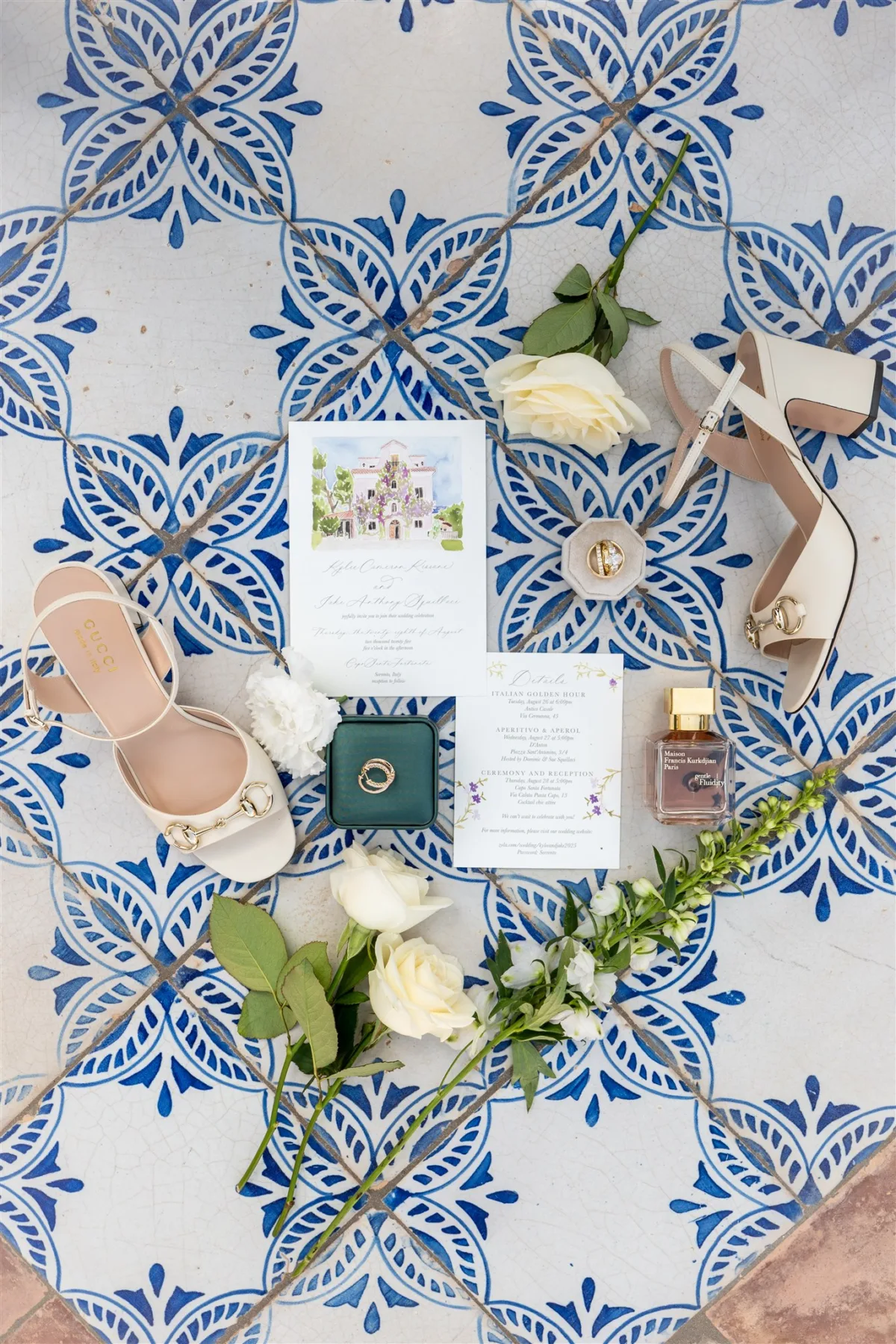 amalfi coast destination wedding planning engaging events by ali sorrento italy - An Effortless Amalfi Coast Celebration Elegant wedding details flatlay on blue Mediterranean tiles featuring invitation suite, nude wedding shoes, wedding rings, and white roses for Amalfi Coast destination wedding planned by Engaging Events by Ali in Sorrento Italy