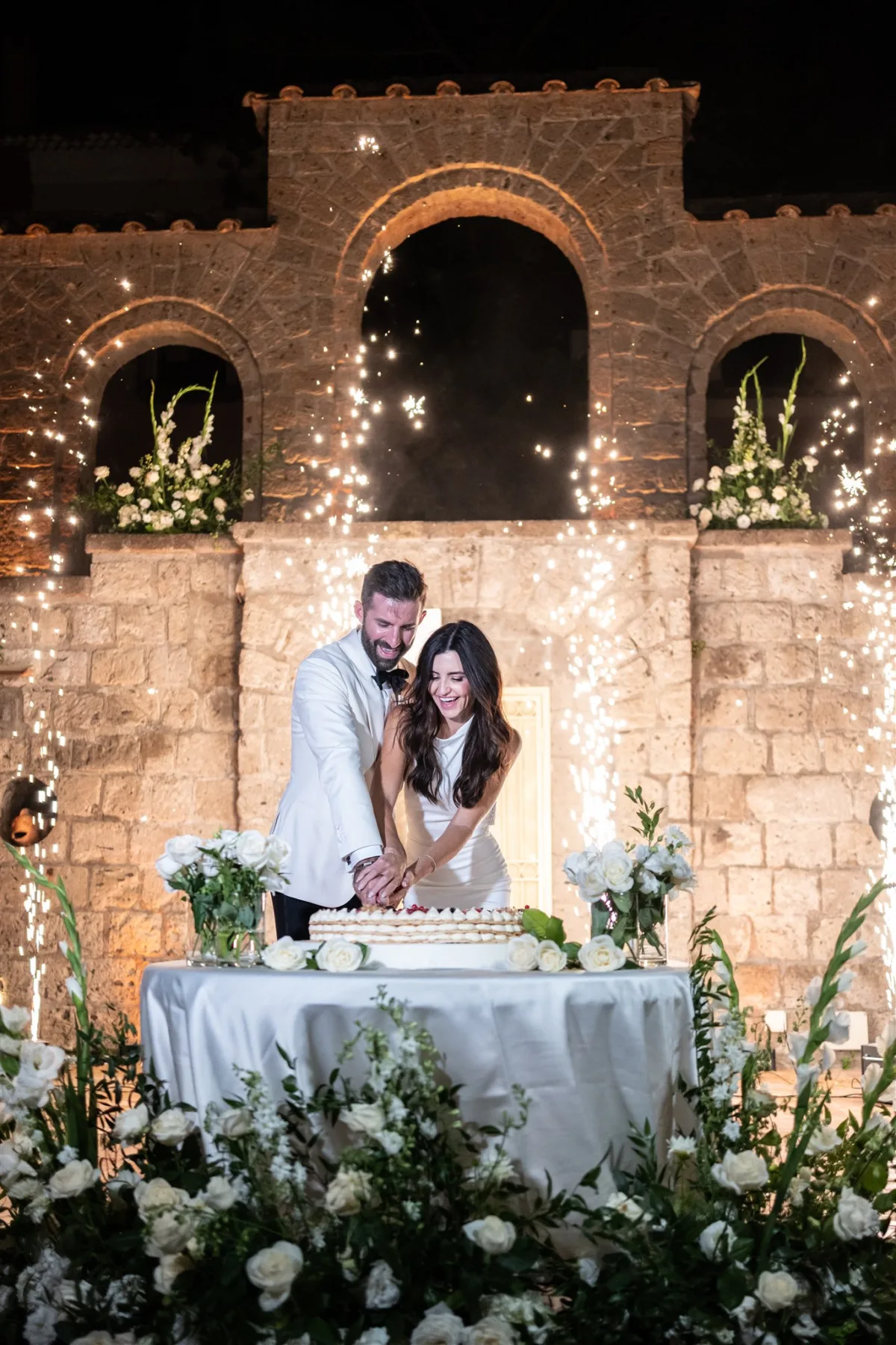 amalfi coast wedding cake cutting capo santa fortunata engaging events - An Effortless Amalfi Coast Celebration Bride and groom cutting wedding cake with sparklers at Capo Santa Fortunata venue in Sorrento Italy, planned by Engaging Events by Ali
