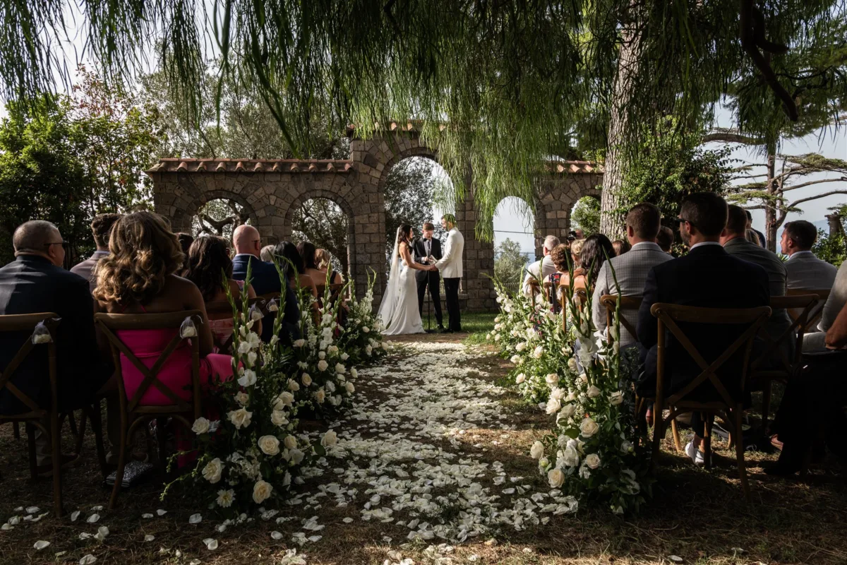 amalfi coast wedding ceremony engaging events ali capo santa fortunata - An Effortless Amalfi Coast Celebration Outdoor wedding ceremony at Capo Santa Fortunata in Sorrento Italy with stone arch backdrop and white floral arrangements planned by Engaging Events by Ali