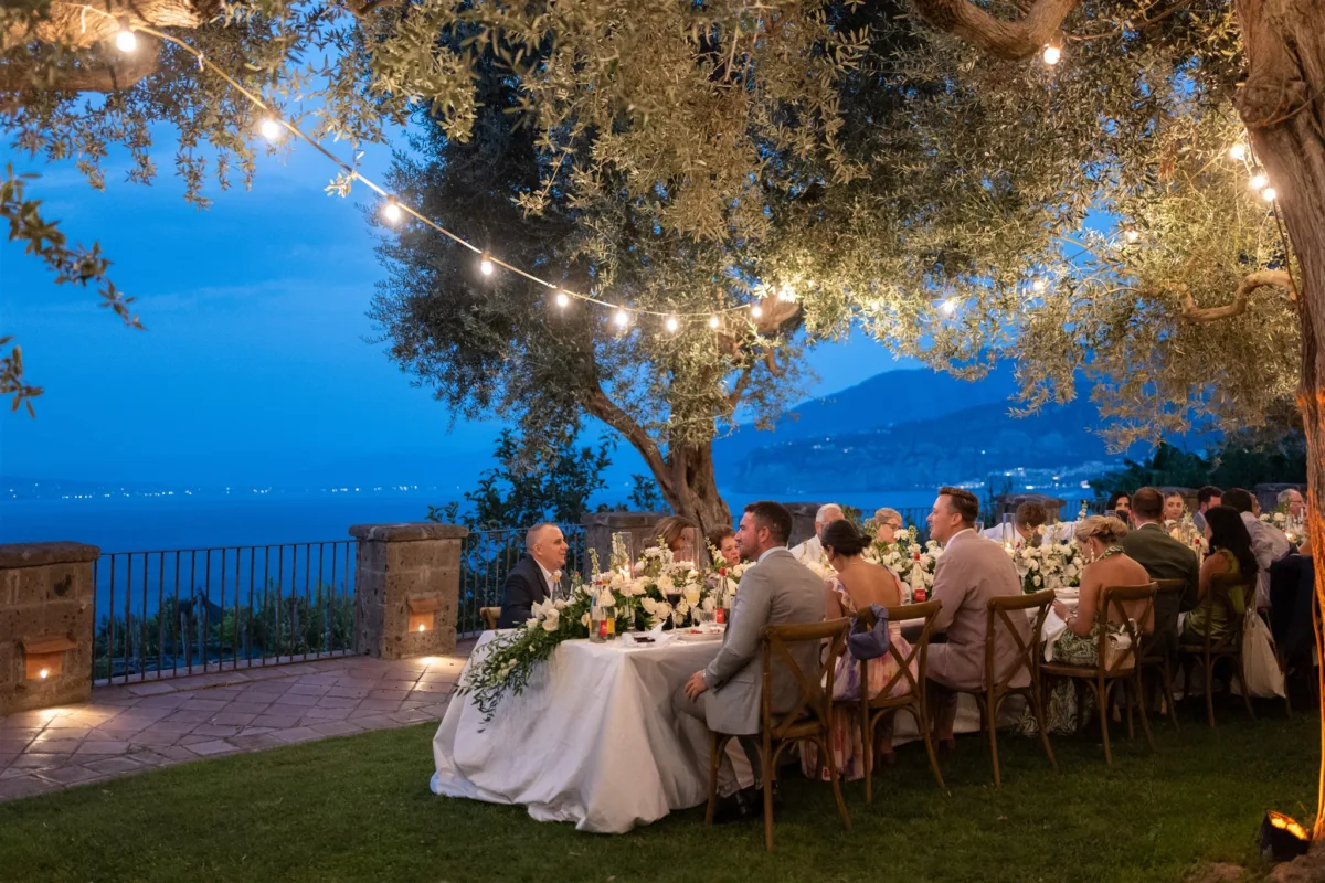 amalfi coast wedding planning engaging events ali capo santa fortunata reception - An Effortless Amalfi Coast Celebration Romantic outdoor wedding reception at Capo Santa Fortunata in Sorrento Italy with string lights and mountain views planned by Engaging Events by Ali