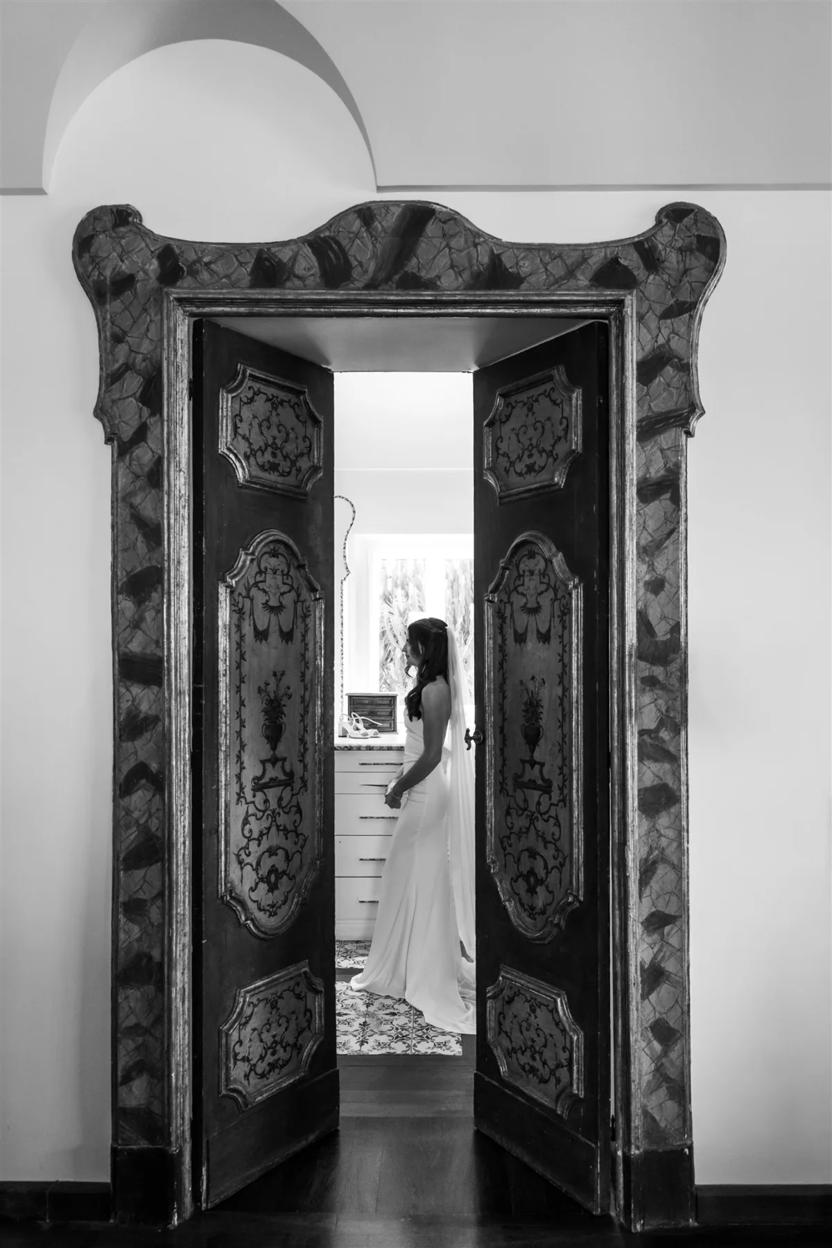 amalfi coast wedding planning engaging events ali capo santa fortunata sorrento 1 - An Effortless Amalfi Coast Celebration Bride in elegant wedding gown walking through ornate Italian doorway at Capo Santa Fortunata venue in Sorrento during Amalfi Coast destination wedding planned by Engaging Events by Ali