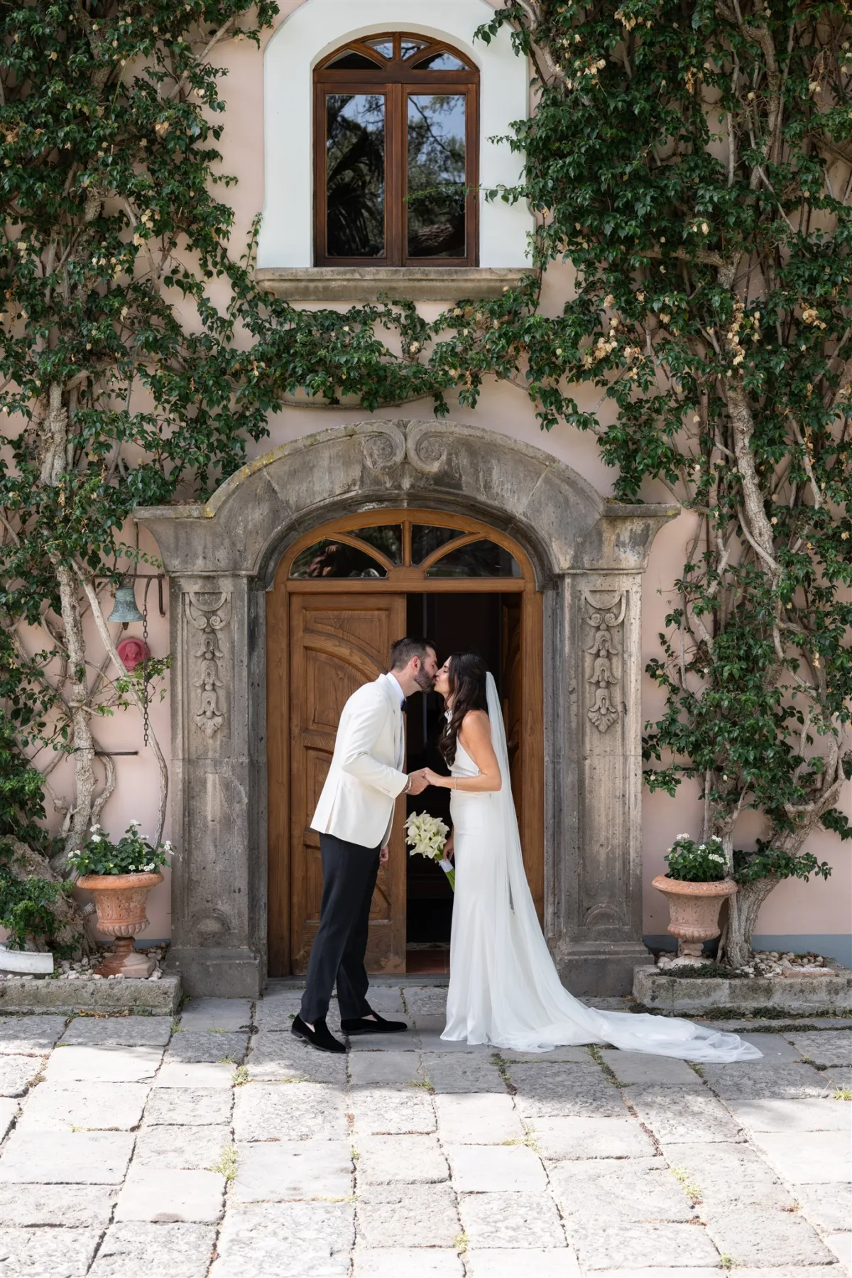 amalfi coast wedding planning engaging events ali sorrento italy - An Effortless Amalfi Coast Celebration Bride and groom kissing at ivy-covered villa entrance during Amalfi Coast wedding planned by Engaging Events by Ali in Sorrento Italy