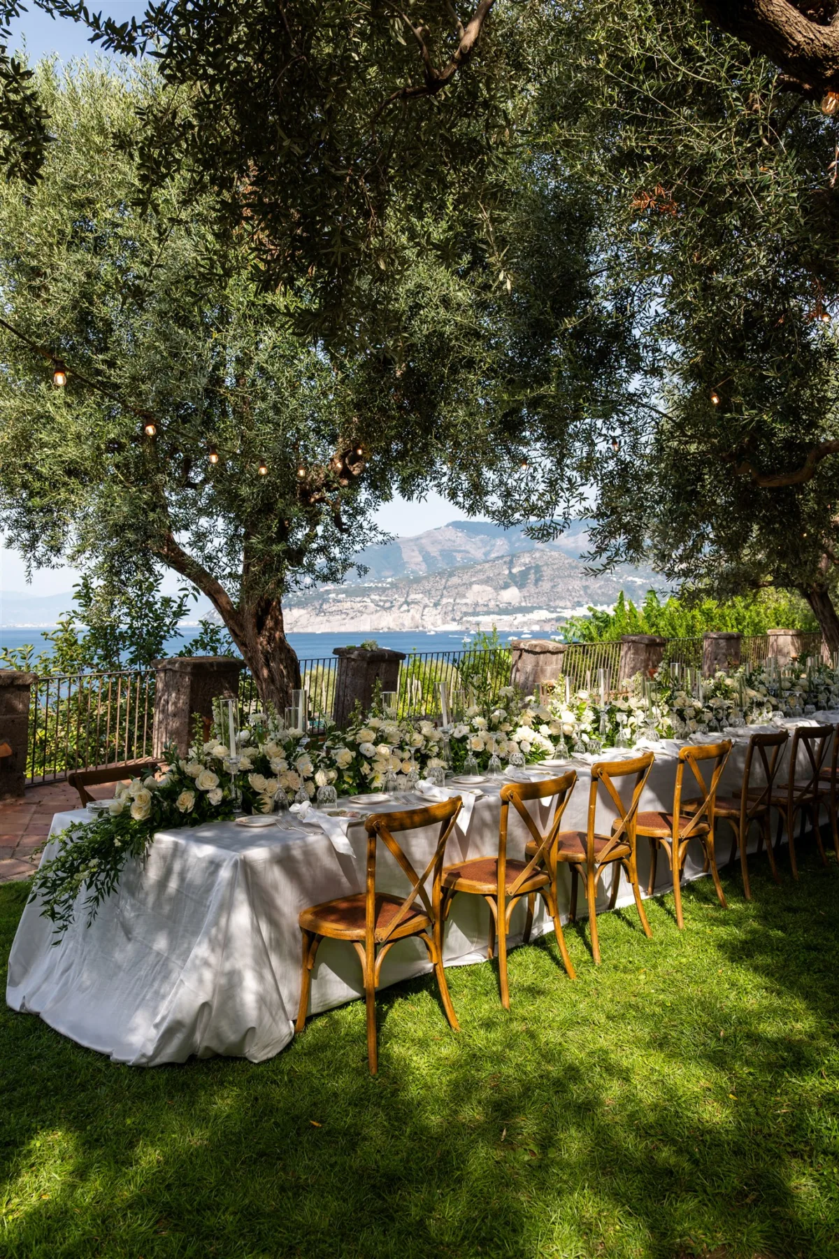 amalfi coast wedding planning engaging events by ali capo santa fortunata - An Effortless Amalfi Coast Celebration Elegant outdoor wedding reception table with white florals under olive trees overlooking the Mediterranean Sea in Sorrento Italy, planned by Engaging Events by Ali at Capo Santa Fortunata venue