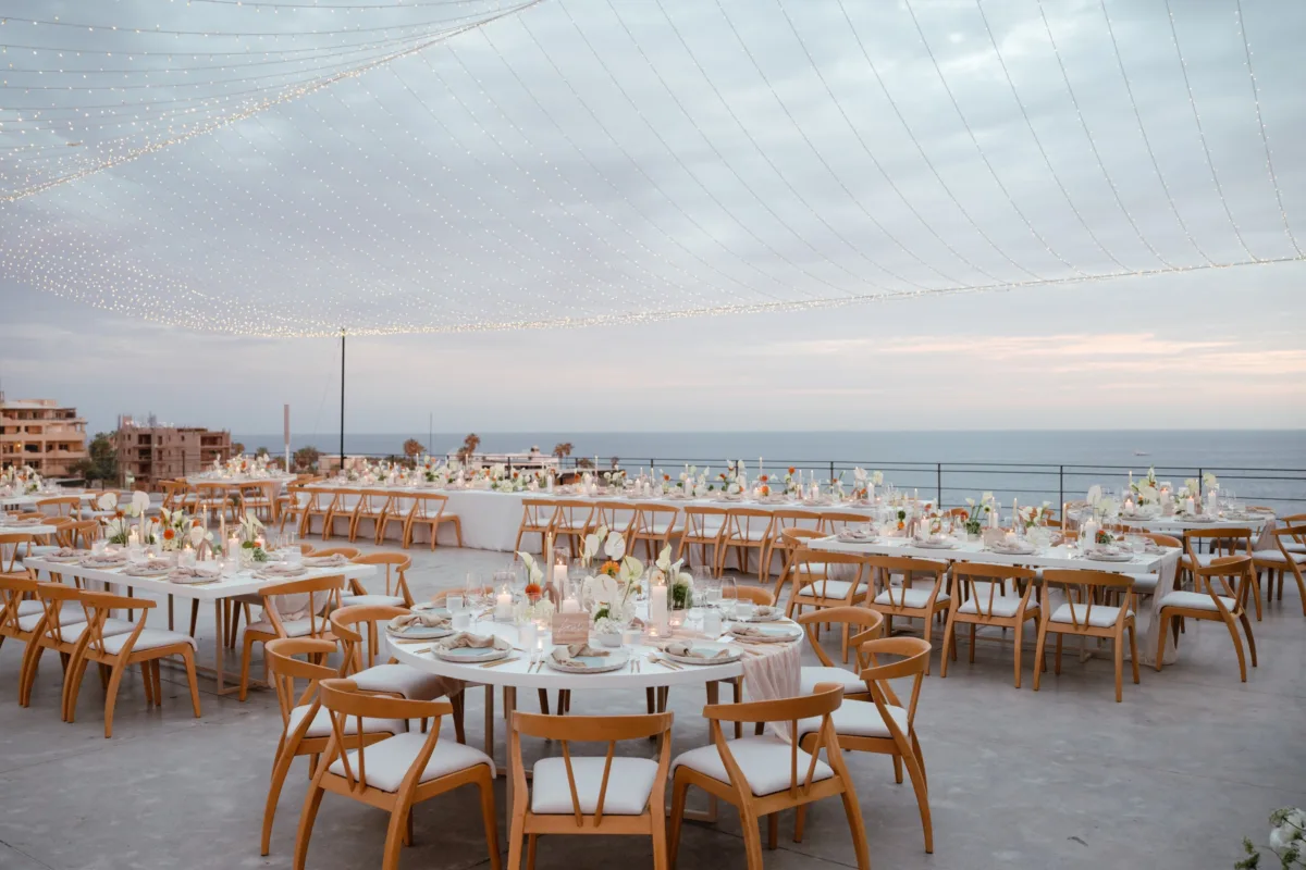 cabo destination wedding reception setup the cape thompson hotel - Luxury Cabo Wedding at The Cape, a Thompson Hotel Elegant oceanfront wedding reception setup with wooden chairs and string lights at The Cape Thompson Hotel in Cabo