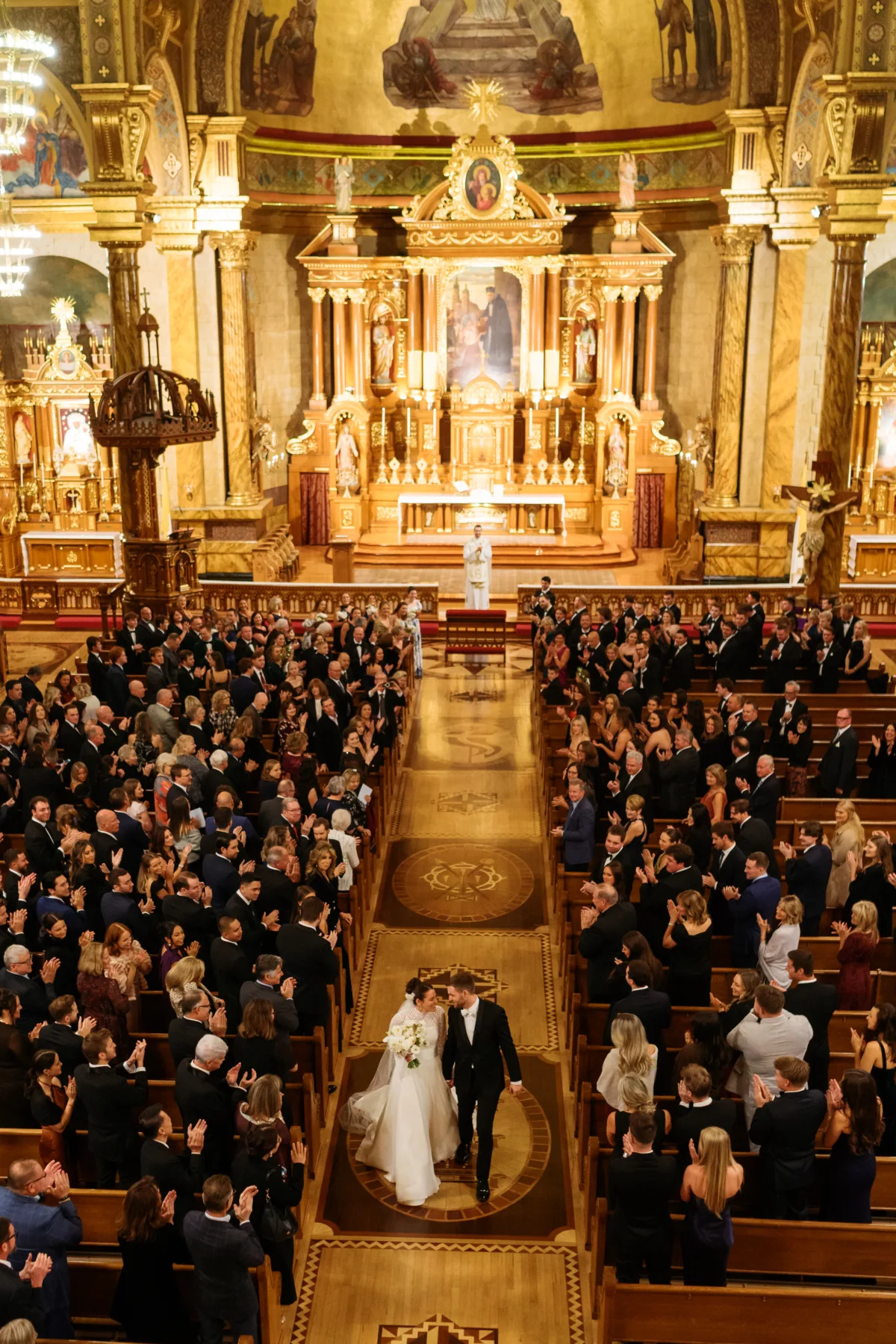 chicago wedding ceremony engaging events ali wedding planning - A Golden Ritz-Carlton Chicago Celebration Bride and groom walking down ornate church aisle after cathedral wedding ceremony in Chicago, coordinated by Engaging Events by Ali