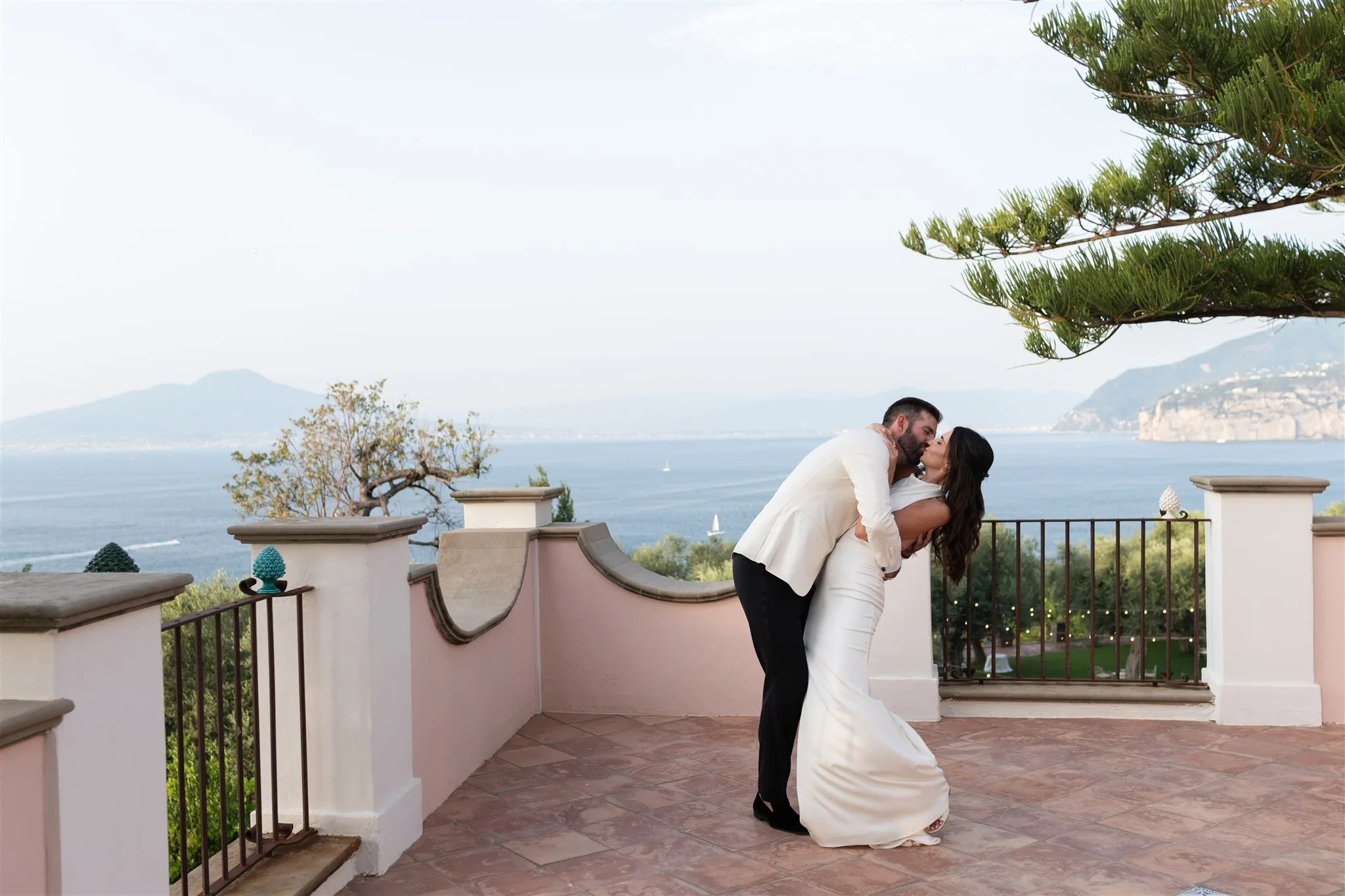 Romantic wedding couple kissing on Mediterranean terrace overlooking Amalfi Coast at Capo Santa Fortunata venue planned by Engaging Events by Ali