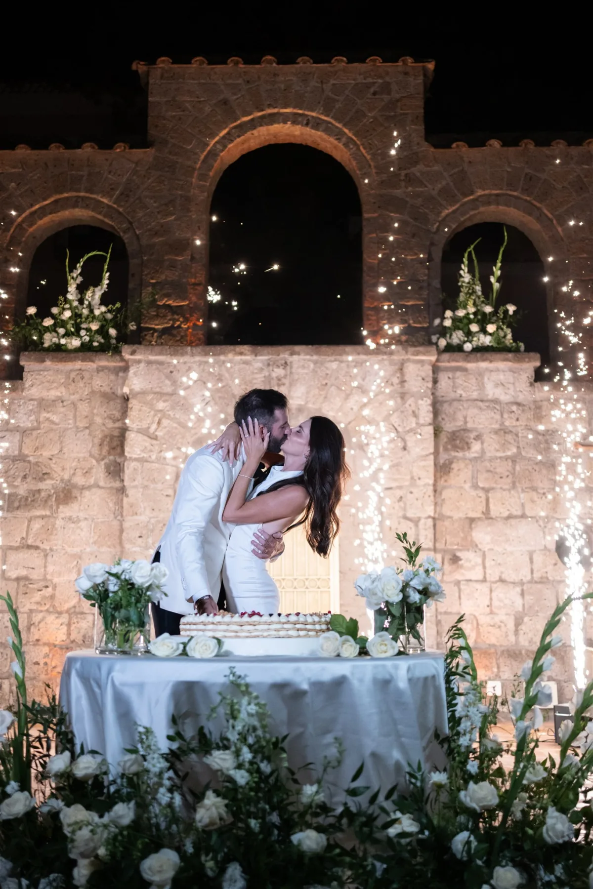 engaging events by ali wedding planning capo santa fortunata amalfi coast cake cutting - An Effortless Amalfi Coast Celebration Romantic cake cutting moment at Capo Santa Fortunata venue in Amalfi Coast Italy planned by Engaging Events by Ali with string lights and floral arrangements