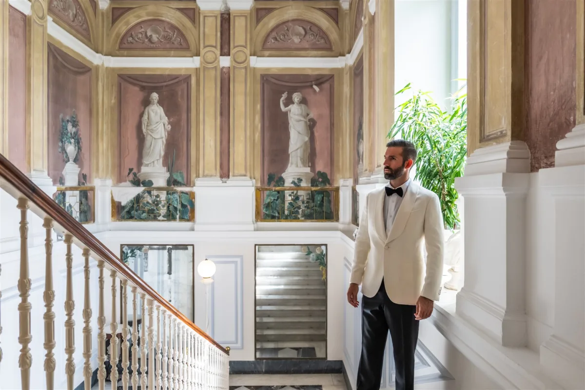 groom portrait capo santa fortunata sorrento italy destination wedding - An Effortless Amalfi Coast Celebration Groom in white dinner jacket standing in elegant Italian villa staircase at Capo Santa Fortunata Sorrento destination wedding planned by Engaging Events by Ali