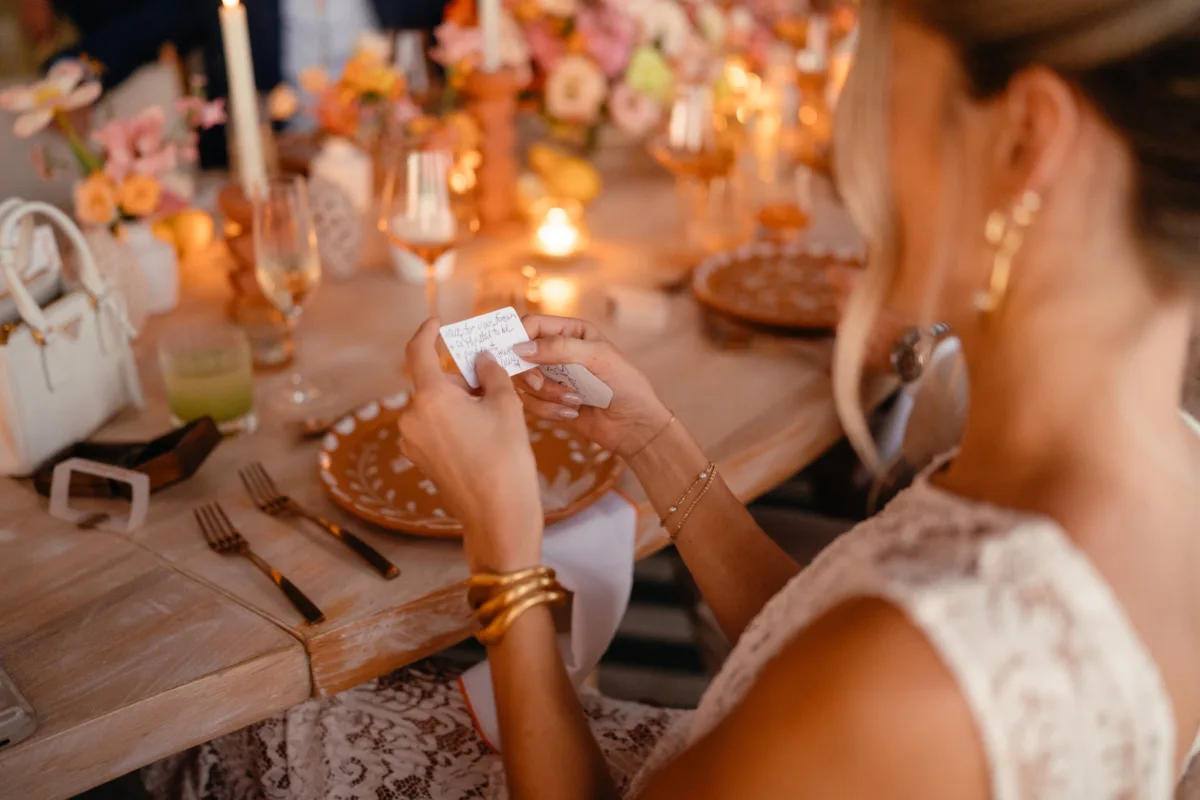 luxury cabo wedding planning engaging events by ali thompson hotel - Luxury Cabo Wedding at The Cape, a Thompson Hotel Bride reading wedding note at elegant tablescape during luxury Cabo destination wedding at The Cape Thompson Hotel planned by Engaging Events by Ali