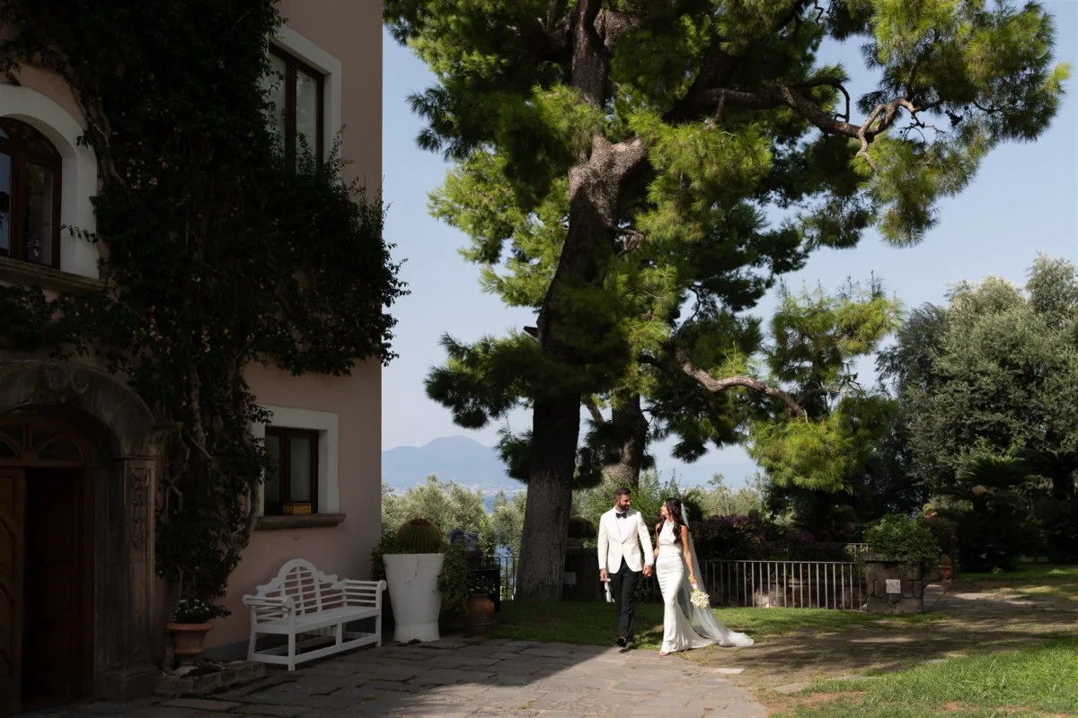 wedding planning engaging events by ali amalfi coast villa capri santafortunata - An Effortless Amalfi Coast Celebration Bride and groom walking hand in hand through elegant villa gardens at Capo Santa Fortunata in Sorrento Italy, planned by Engaging Events by Ali wedding planner